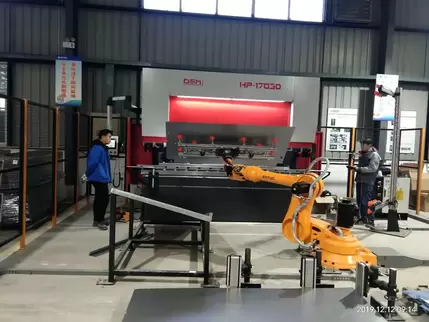 奥斯玛HP-17030液压数控折弯机客户现场实拍：设备搭载自动化机械手实现智能上下料，专业工程师操作1700吨级液压折弯系统，集成双缸同步技术与智能数控系统，完成4米超长板材±0.02mm级精密成型，展现高端数控装备在工业自动化领域的核心应用价值