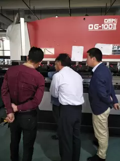 奥斯玛OG-100II下动式液压数控折弯机客户现场实拍：专业操作人员正在执行高精度金属板材折弯作业，设备搭载智能数控系统与液压同步技术，可实现复杂工件±0.01mm级加工精度，展现高端数控装备在钣金制造领域的实际应用价值