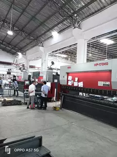 奥斯玛HP-17040大型液压数控折弯机客户现场实拍：专业工程师操作1700吨级液压折弯设备，搭载智能数控系统与双缸同步技术，实现4米超长板材一次性精密成型，加工精度达±0.02mm，展现高端数控装备在重型钣金制造领域的核心应用价值