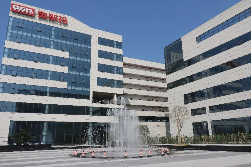 奥斯玛智能装备生产园区景观，大楼前设有花园喷泉，现代工业建筑与绿意园林融合，展现智能制造企业环境美学